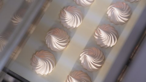 Beautiful creamy vanilla marshmallows come from a machine. Conveyor belt with fresh zephyr desserts. Close up. Top view.