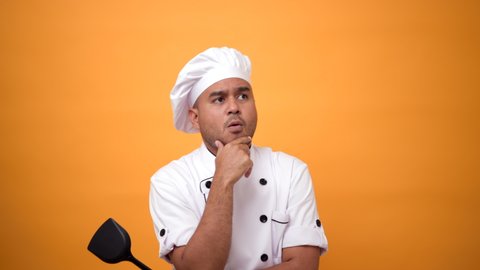 Portrait of unhappy man chef thinking with pan and turner with a serious expression on isolated yellow background.
