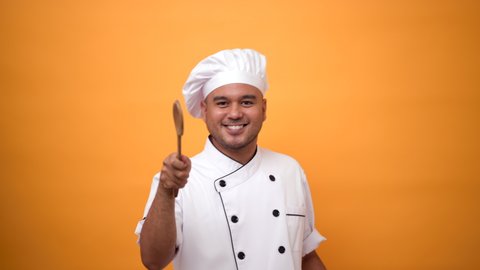 Portrait happy funny man chef holding turner and dancing isolated on yellow background.