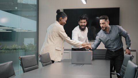 Multinational business group of diverse people looking at laptop screen winning victory happy stack hands put palms together united different ethnicity employees support trust and teambuilding concept