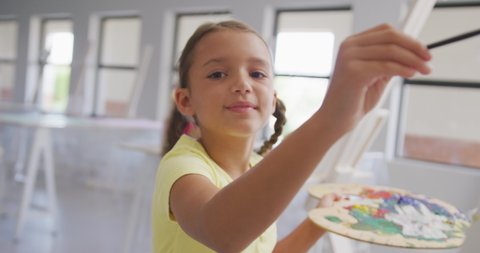 Video of smiling caucasian girl painting during art lessons at school. primary school education, knowledge and learning concept.