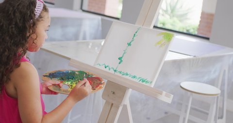 Video of back of caucasian girl painting during art lessons at school. primary school education, knowledge and learning concept.