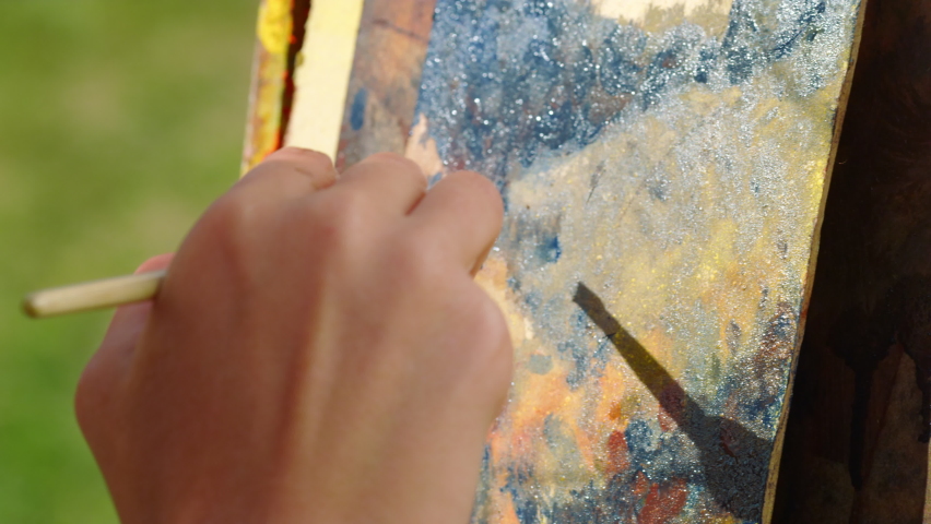 Closeup talented woman hand creating masterpiece on canvas. Unknown creative painter drawing mountains oil paints paintbrush outdoor. Unrecognizable artist painting picture outside. Craft art concept
