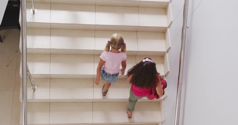 Video of top view of diverse girls walking upstairs at school. primary school education, learning and socializing concept.