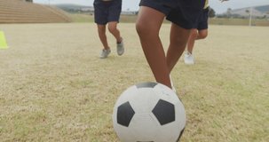 Video of legs of diverse girls playing soccer in front of school. primary school education, sport and exercising concept.