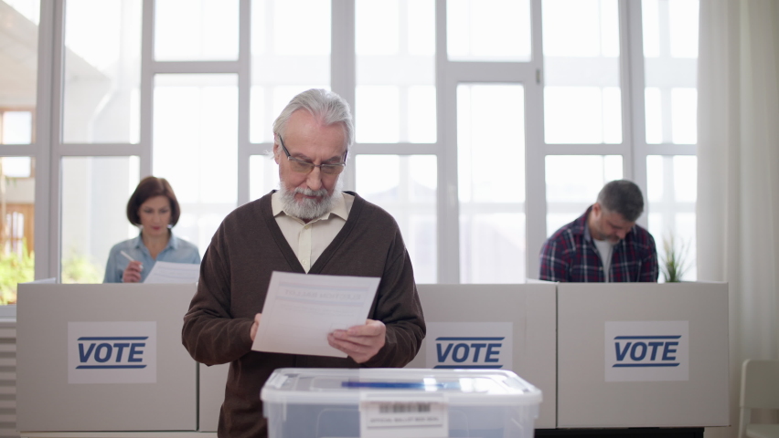 People voting at polling station, throwing ballots into the box, elections day Royalty-Free Stock Footage #1088588481