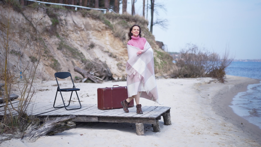 Confident excited woman spinning in slow motion looking at camera standing on pier outdoors. Wide shot portrait of happy positive Caucasian tourist enjoying sunny day outdoors posing