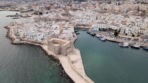 Aerial drone shot of a castle with a wall on the coastline of Monopoli, Italy.