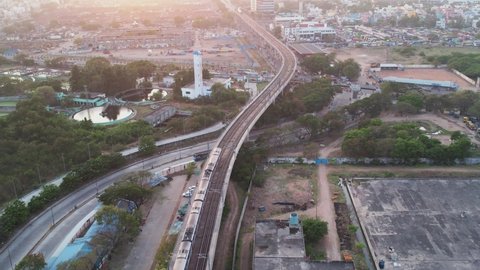 Aerial view of Koyambedu is situated in the western part of Chennai city. Shows 2 metro rails crossing Koyambedu market during pleasant sunset. Which shows city's view with buildings and vehicles.