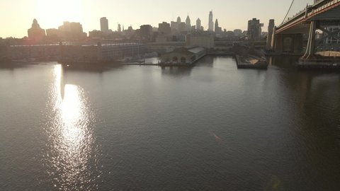 Glistening Water Of Delaware River At Dusk With Benjamin Franklin Bridge And Skyline In Philadelphia. - aerial ascend, forward