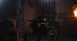 A blacksmith in protective gear and goggles saws off part of a metal workpiece using a flex, metal sparks fly in different directions, close-up, dynamic video. 4k video, red komodo