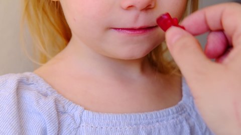 close-up of part of small child, blonde girl 3 years old wants to eat gelatinous sweets, gummy bear, kid has a good appetite, happy childhood, balanced diet, sweet life, unhealthy food, halal food