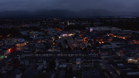 Slide and pan shot of colourful buildings in evening town. Aerial shot of city centre after sunset. Killarney, Ireland