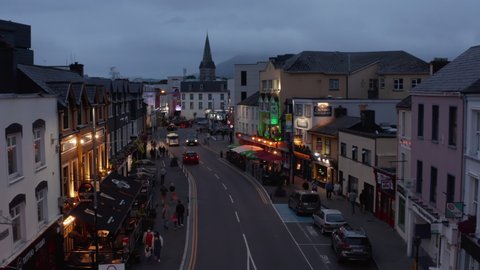 People walking in evening town. Outdoor terraces in front of restaurants on street. City at dusk. Killarney, Ireland in 2021