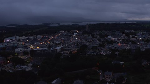 Aerial panoramic footage of evening town under overcast sky. Lake and cloud shrouded hills in distance. Killarney, Ireland