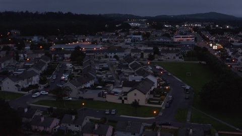 Aerial footage of residential houses in suburbs. Fly above rows of buildings at dusk. Killarney, Ireland