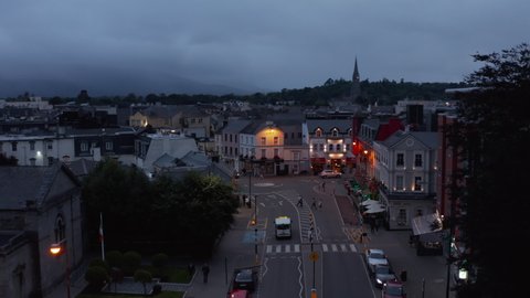 Descending footage of street in evening town. Road with crosswalk and flashing warn lights. Killarney, Ireland in 2021