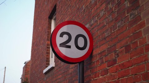 20mph stop sign against a red brick wall, 4K handheld footage
