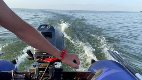 Man drives a motorised rubber inflatable boat. Close-up of hand and engine. Planing. Waves on the water. Boat trip at high speed. The concept of freedom and movement. Fishing trip.