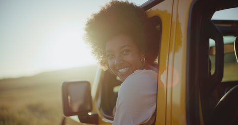 Beautiful young black african american woman smiling at sunset on summer road trip, travel and adventure lifestyle