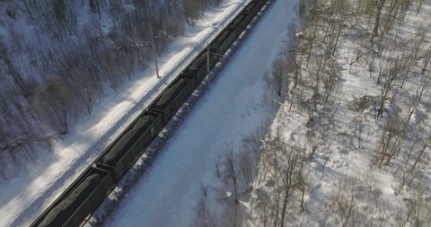 Freight train with coal on winding two-sided in wild mountains landscape through a difficult part of Trans Siberian railways - Aerial drone view at winter sunny frozen day