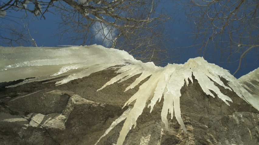 Frozen icicles hang on the rocks, time lapse.