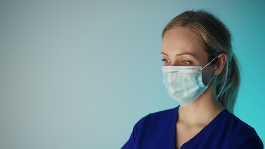 European woman nurse in her 30s looking to the camera while wearing facial mask that covers her mouth and nose. High quality 4k footage Royalty-Free Stock Footage #1088605303