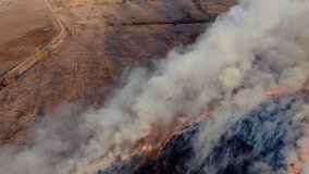 Epic aerial view of smoking wild fire. Large smoke clouds and fire spread. Dry grass burning. Climate change, ecology, earth