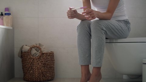 Stressed unrecognizable woman sitting on toilet and waiting for pregnancy test results. Shot with RED helium camera in 8K