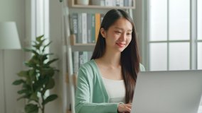 Young Asian woman using laptop computer for online working, studying, learning chatting in social media at home.