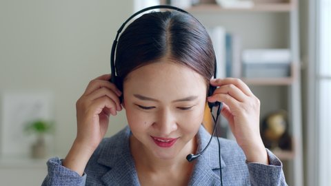 Close up of Young Asian businesswoman, call center, customer service wearing headphone and smiling. Look at camera
