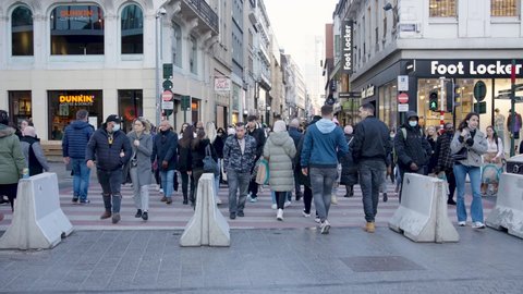 Brussels , Belgium - 03 20 2022: People crossing pedestrian walkway. Multicultural faces men and women walking in city center - Slow motion