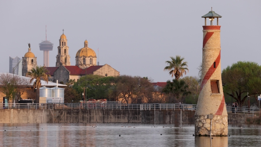 San Antonio, Texas skyline at sunset seen from Woodlawn Lake Park with the lake and old brick lighthouse in the foreground.