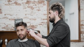 Man barber cutting hair of male client with clipper at barber shop. Hairstyling process. Slow motion Close up. High quality FullHD footage