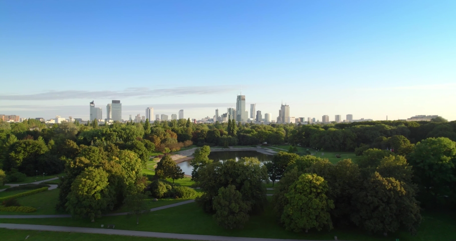 City park with the city center in the background. Aerial view of offices in skyscrapers over the panorama of Warsaw in a urban park. Lake in the park with green trees during summer. | Shutterstock HD Video #1088621301
