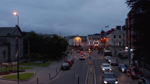 Aerial ascending shot of town at twilight, overcast sky. Vehicles passing through street. Killarney, Ireland in 2021