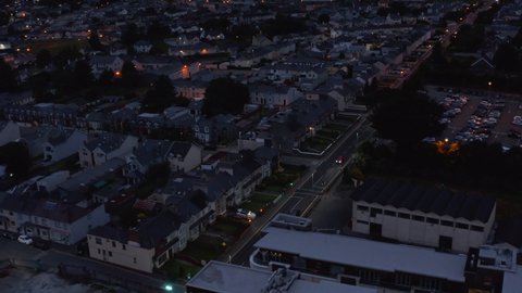 Fly above urban neighbourhood after sunset. residential buildings along straight street. Killarney, Ireland
