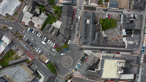 Aerial birds eye overhead top down ascending view of cars passing through roundabout in town centre. Town development from height. Ennis, Ireland