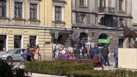 Krakow, Malopolska, Poland - March 2022: Krakow, Poland, a traditional horse carriage rides on a sunny day along the street of the Old Town, tours of Krakow, tourist attractions