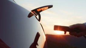 Unrecognizable businessman plugging electric car from charging station. Senior plugging in power cord to electric car at cinematic sunset. Businessman charging electric car at outdoor charging station - Powered by Shutterstock - Get 15% off with code: PIKWIZARD15
