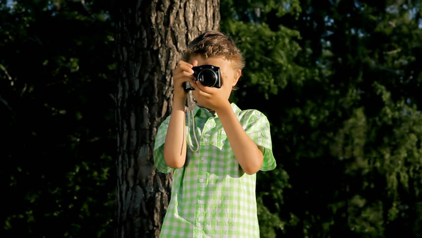 boy with a camera takes pictures outdoors in summer