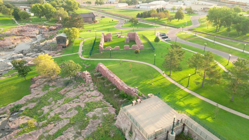 Aerial view of Falls Park in South Dakota. Walking trails and observation point. Preserved pieces from the old mill. Shadows from the sun.  Water flowing from the falls. 