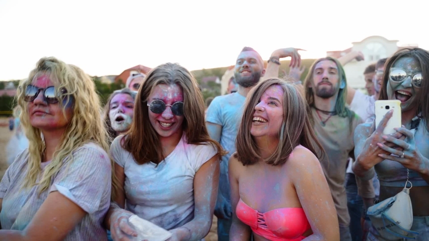 Joyful people smeared in colorful powder have fun, take selfie, play with dry colors to celebrate Holi festival. Outdoor hindu holiday party. End of lockdown, covid pandemic, restrictions. Royalty-Free Stock Footage #1088627449