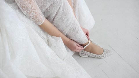 bride in a wedding dress puts on flat shoes	