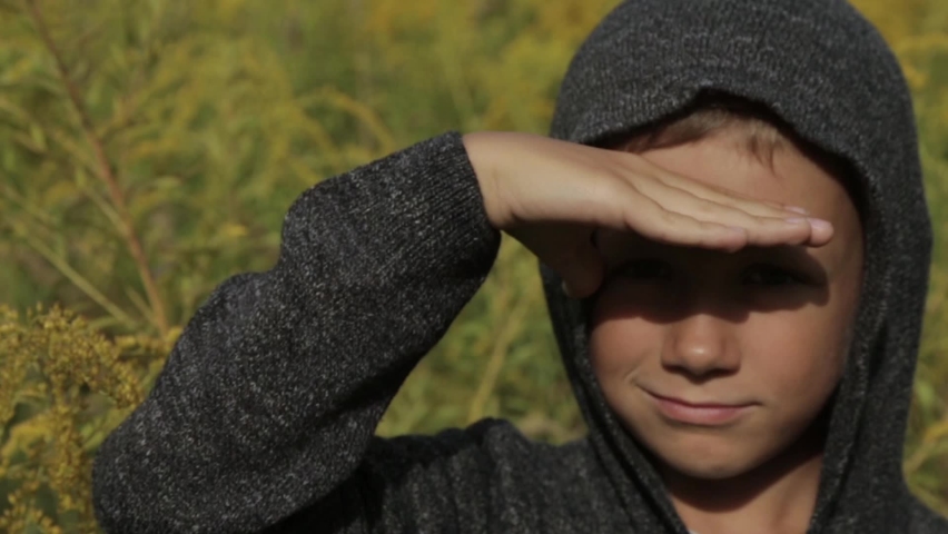 Cute boy in a grey hoodie outdoors