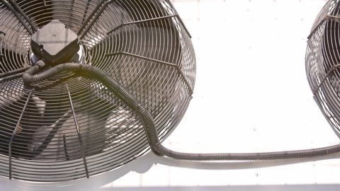 outdoor air conditioner condenser electrical fan spinning, decelerating and accelerating, extreme closeup