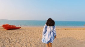 4K video of Beautiful landscape of tropical beach with one Indian woman with open arms walking to the sea. Happy traveler woman in white dress enjoys her tropical beach vacation