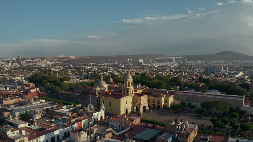 Colonial style city. Center of wine production in Mexico. Aerial drone view of old historical city with cathedral and famous cultural buildings. Sunset time over main tourist destination Queretaro Royalty-Free Stock Footage #1088645391