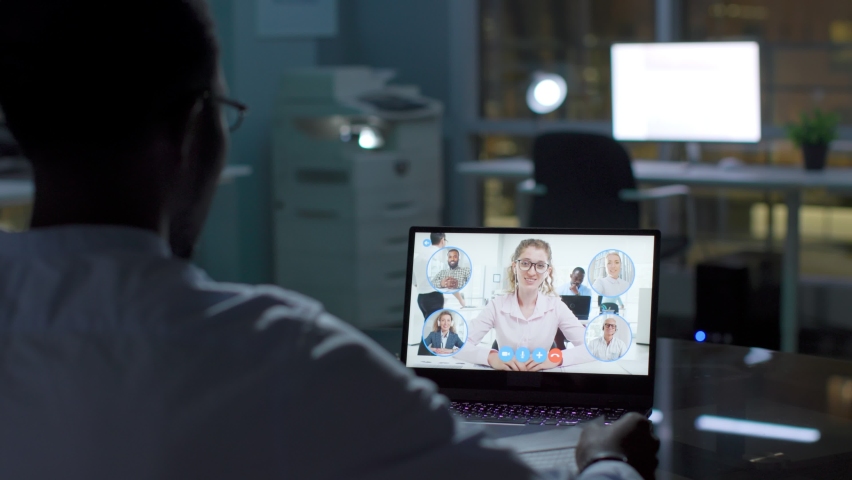 Back view of African-American businessman having video conference late in office. Entrepreneur having video chat with colleagues, a Business & Finance Video by nimito