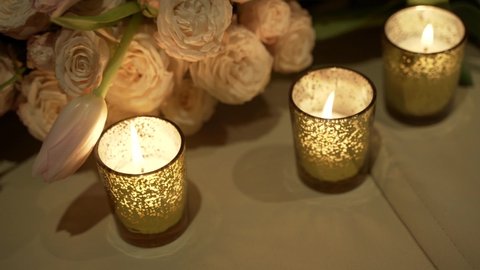 Close-up of burning candles and flower bunch. Romantic date